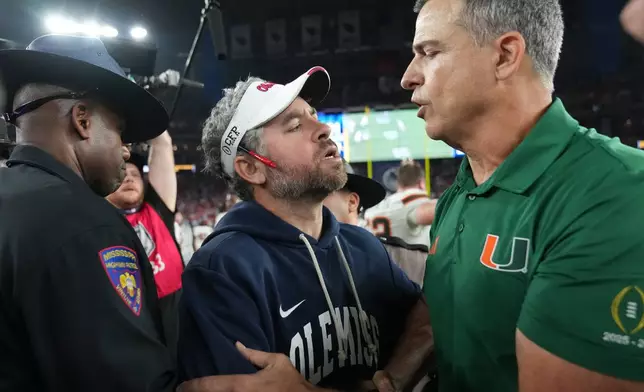 CORRECTS TO MISSISSIPPI HEAD COACH PETE GOLDING NOT MISSISSIPPI HEAD COACH MARIO CRISTOBAL - Mississippi head coach Pete Golding, center, greets Miami head coach Mario Cristobal, right, after the Fiesta Bowl NCAA college football playoff semifinal game, Thursday, Jan. 8, 2026, in Glendale, Ariz. (AP Photo/Rick Scuteri)