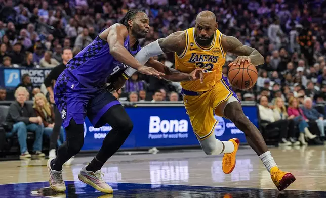 Los Angeles Lakers forward LeBron James, right, dribbles against Sacramento Kings forward Precious Achiuwa (9) during the first half of an NBA basketball game, Monday, Jan. 12, 2026, in Sacramento, Calif. (AP Photo/Justine Willard)