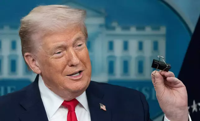 President Donald Trump holds a binder clip as he speaks during a press briefing at the White House in Washington, Tuesday, Jan. 20, 2026. (AP Photo/Mark Schiefelbein)