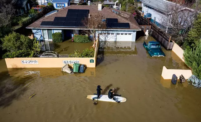 People paddle through a street flooded by the "King Tides", occurring when the sun, moon and Earth align, causing a stronger gravitational pull Saturday, Jan. 3, 2026, near Corte Madera in Marin County, Calif. (AP Photo/Ethan Swope)
