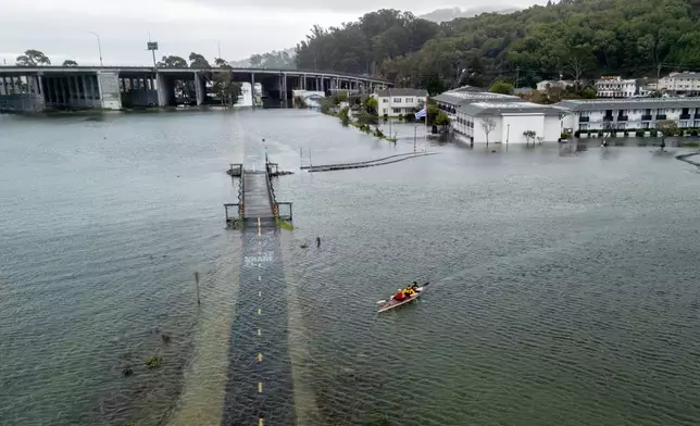 From front, brothers Connor and Brett Cardinal, and friend Eli Ferrell kayak towards a flooded Mill Valley-Sausalito Path during king tide in Mill Valley, Calif., Saturday, Jan. 3, 2026. (Stephen Lam /San Francisco Chronicle via AP)