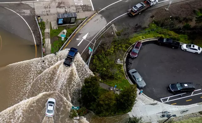 Vehicles drive on a flooded road during a king tide event in Corte Madera, Calif., Saturday, Jan. 3, 2026. (Stephan Lam/San Francisco Chronicle via AP)