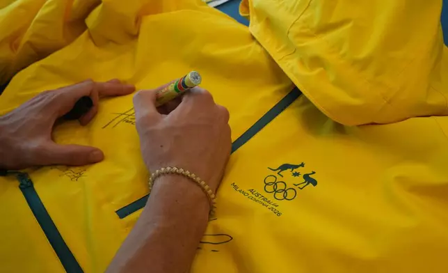 Australia's Hugo Hinckfuss signs the jacket at the AIS European Training Centre in Gavirate, on the Varese lake, northern Italy, Monday, Jan. 26, 2026. (AP Photo/Antonio Calanni)
