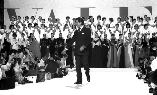 FILE - As models and collaborators clap hands, Valentino Garavani salutes cheering guests after he presented his Fall-Winter 1986-1987 High Fashion collection on July 25, 1986 in Rome. (AP Photo/Gianni Foggia, File)