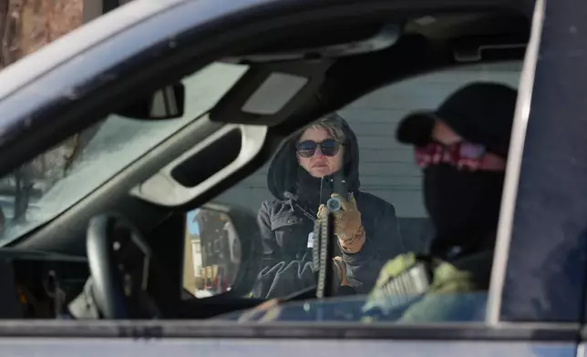 A person photographs a federal agent inside their vehicle on Thursday, Jan. 29, 2026, in North Minneapolis. (AP Photo/Adam Gray)