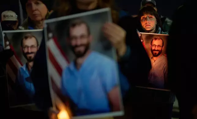 People hold up photos during a vigil for Alex Pretti, who was shot and killed by federal immigration enforcement in Minneapolis, Wednesday, Jan. 28, 2026, in Henderson, Nev. (AP Photo/John Locher)