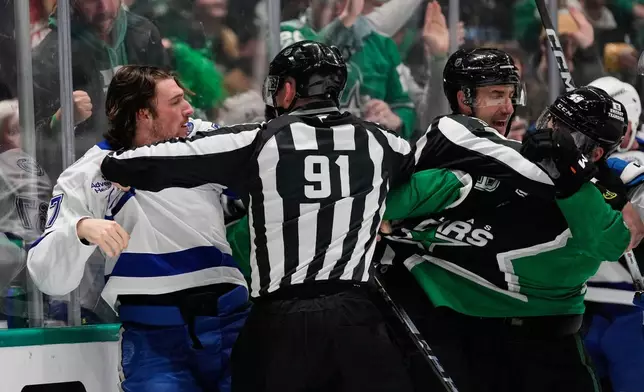 Tampa Bay Lightning defenseman Declan Carlile, left, is held back by linesman Ben O'Quinn (91) as Carlile and Dallas Stars' Justin Hryckowian, right, fight in the first period of an NHL hockey game in Dallas, Sunday, Jan. 18, 2026. (AP Photo/Tony Gutierrez)