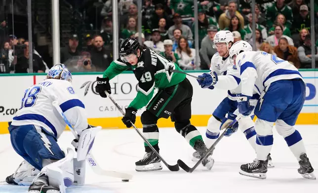 Dallas Stars center Justin Hryckowian (49) takes a shot as Tampa Bay Lightning goaltender Andrei Vasilevskiy, left, Declan Carlile, rear, and Maxwell Crozier (24) defend in the first period of an NHL hockey game in Dallas, Sunday, Jan. 18, 2026. (AP Photo/Tony Gutierrez)