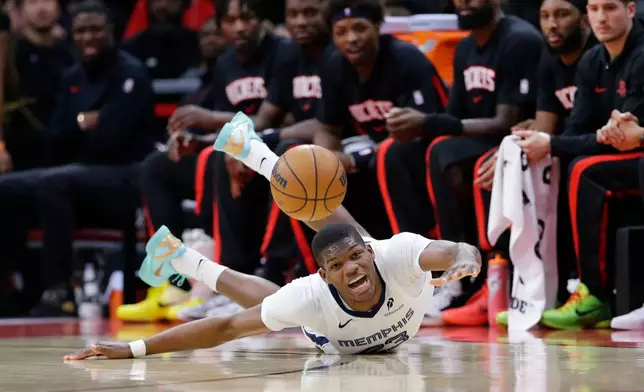 Memphis Grizzlies forward Cedric Coward reacts as he loses the ball after slipping on the court in front of the Houston Rockets bench during the first half of an NBA basketball game Monday, Jan. 26, 2026, in Houston. (AP Photo/Michael Wyke)