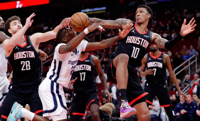 Memphis Grizzlies forward Cedric Coward, center, has his shot attempt blocked by Houston Rockets forward Jabari Smith Jr. (10) as center Alperen Sengun (28) looks on during the first half of an NBA basketball game Monday, Jan. 26, 2026, in Houston. (AP Photo/Michael Wyke)
