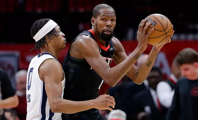 Houston Rockets forward Kevin Durant, right, looks to drive around Memphis Grizzlies forward Jaylen Wells, left, during the first half of an NBA basketball game Monday, Jan. 26, 2026, in Houston. (AP Photo/Michael Wyke)