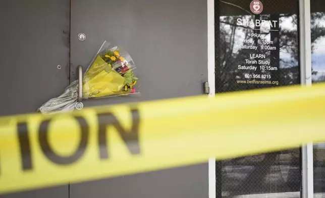 Caution tape and flowers cover the entrance to the Beth Israel Congregation, a synagogue that was set on fire early Saturday morning, on Monday, Jan. 12, 2026, in Jackson, Miss. (AP Photo/Sophie Bates)
