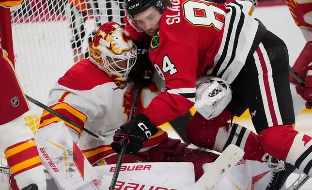 Chicago Blackhawks left wing Landon Slaggert, right, collides with Calgary Flames goaltender Devin Cooley during the third period of an NHL hockey game, Thursday, Jan. 15, 2026, in Chicago. (AP Photo/Erin Hooley)