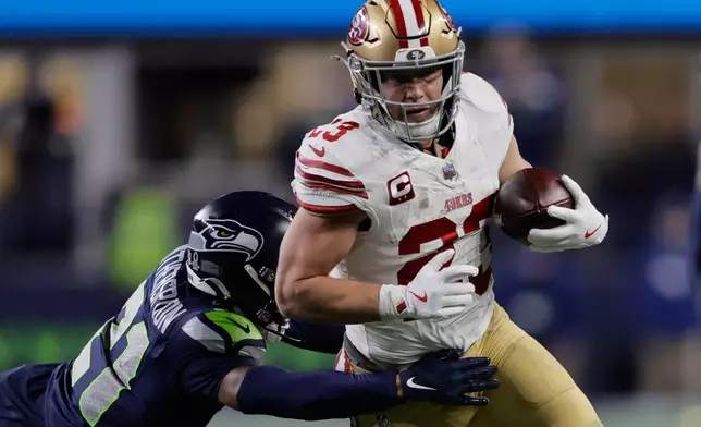 San Francisco 49ers running back Christian McCaffrey (23) tries to get past the Seattle Seahawks cornerback Devon Witherspoon during the first half of an NFL football divisional playoff game Saturday, Jan. 17, 2026, in Seattle. (AP Photo/John Froschauer)