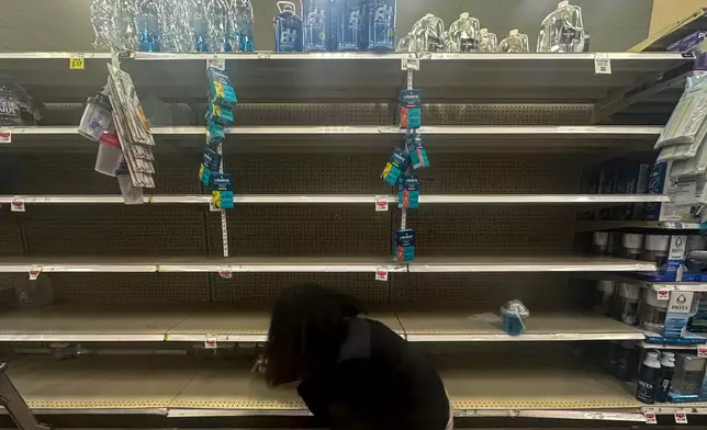 A shopper searches for water on near empty shelves in grocery store ahead of winter weather, Wednesday, Jan. 21, 2026, in Marietta, Ga. (AP Photo/Mike Stewart)