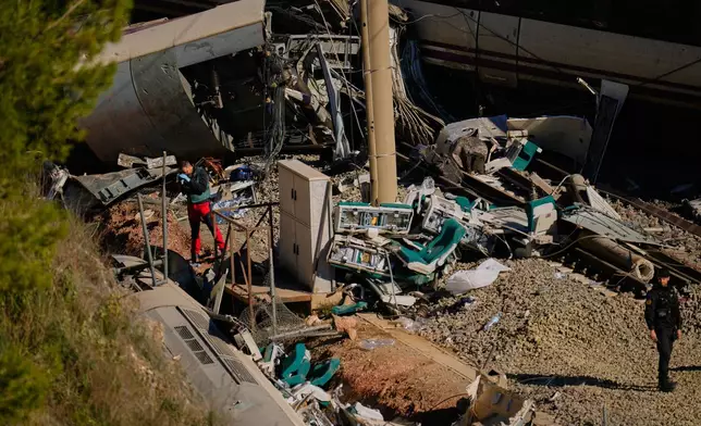 Guardia Civil officers collect evidence next to the wreckage of train cars involved in a collision in Adamuz, southern Spain, Tuesday, Jan. 20, 2026. (AP Photo/Manu Fernandez)