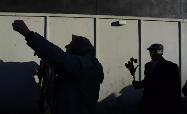Protesters hold up flowers as they demonstrate in support of anti-government protests in Iran, outside Downing Street, in London, Wednesday, Jan. 14, 2026. (AP Photo/Kin Cheung)