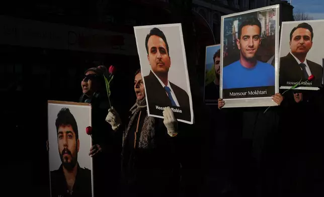 Protesters hold up placards with pictures of victims as they demonstrate in support of anti-government protests in Iran, outside Downing Street, in London, Wednesday, Jan. 14, 2026. (AP Photo/Kin Cheung)
