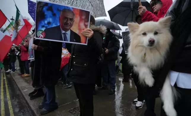 Protesters hold up placards showing Iran’s exiled crown prince Reza Pahlavi as they demonstrate outside the House of Parliament, in London, Tuesday, Jan. 13, 2026. (AP Photo/Kin Cheung)