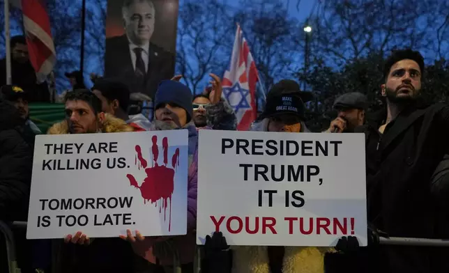 Protesters hold up placards and flags as they demonstrate outside the Iranian Embassy in London, Monday, Jan. 12, 2026. (AP Photo/Alastair Grant)