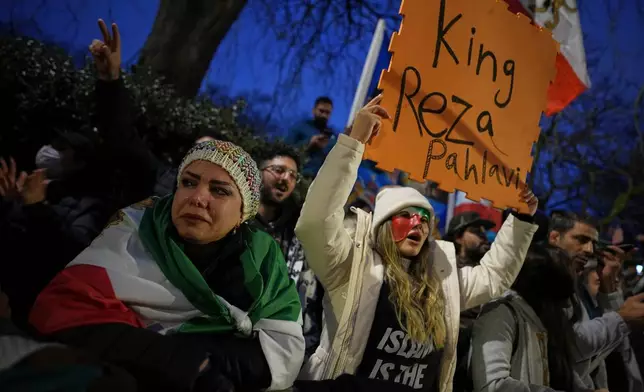 Protesters hold up placards and flags as they demonstrate outside the Iranian Embassy in London, Monday, Jan. 12, 2026. (AP Photo/Alastair Grant)