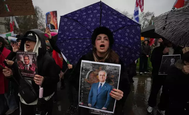 Protesters hold up placards showing Iran’s exiled crown prince Reza Pahlavi as they demonstrate outside the House of Parliament, in London, England, Tuesday, Jan. 13, 2026. (AP Photo/Kin Cheung)