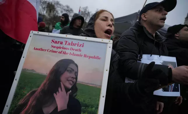 Protesters hold up placards as they demonstrate outside the House of Parliament, in London, England, Tuesday, Jan. 13, 2026. (AP Photo/Kin Cheung)