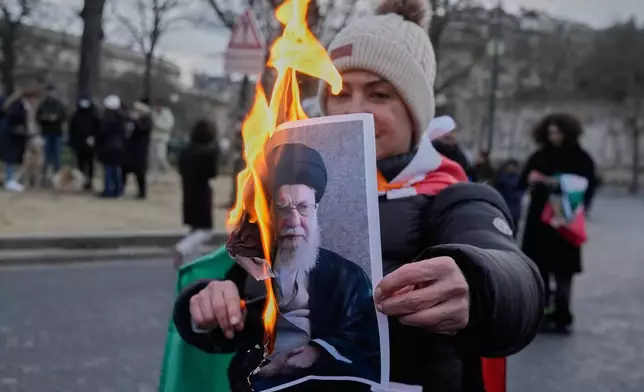 A protester holds a burning poster of Iran's Supreme Leader Ayatollah Ali Khamenei during a rally in support of the nationwide mass demonstrations in Iran against the government, Sunday, Jan. 11, 2026, in Paris. (AP Photo/Michel Euler)