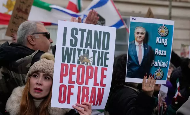 Protesters hold placards during a rally in support of the nationwide mass demonstrations in Iran against the government in Paris, Sunday, Jan. 11, 2026. (AP Photo/Michel Euler)