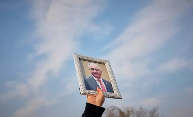 A member of the Iranian community holds a photograph of Iran's exiled crown prince Reza Pahlavi during a rally in support of anti-government protests in Iran, outside the U.S. embassy in Bucharest, Romania, Wednesday, Jan. 14, 2026. (AP Photo/Andreea Alexandru)