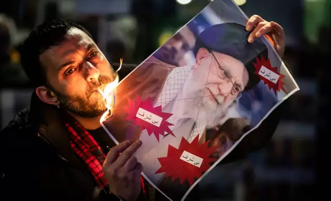 A protester burns an image of the Ayatollah Ali Khamenei with a cigarette during rally in support of the nationwide mass demonstrations in Iran against the government, Tuesday, Jan. 13, 2026 in Zuerich, Switzerland.(Michael Buholzer /Keystone via AP)
