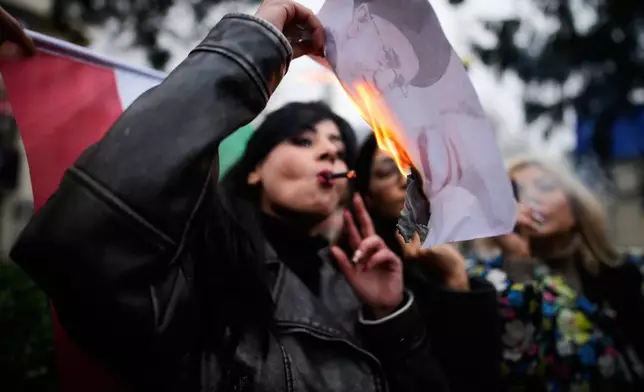 A protester smokes a cigarette after lighting it off a burning poster of Iran's Supreme Leader Ayatollah Ali Khamenei during a rally in support of Iran's anti-government protests, in Yalova, Turkey, Friday, Jan. 16, 2026. (AP Photo/Emrah Gurel)