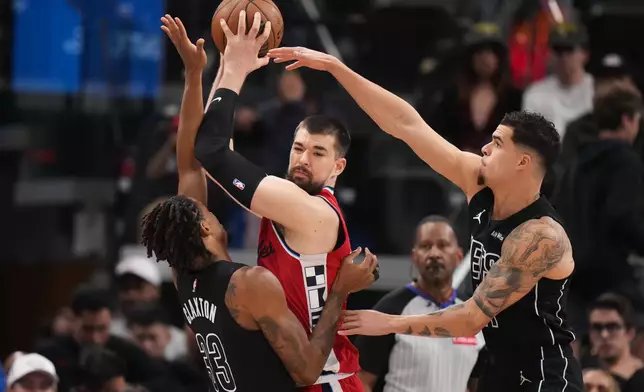 Los Angeles Clippers center Ivica Zubac, center, is defended by Brooklyn Nets center Nic Claxton, left, and forward Michael Porter Jr. during the first half of an NBA basketball game Sunday, Jan. 25, 2026, in Inglewood, Calif. (AP Photo/Jae C. Hong)