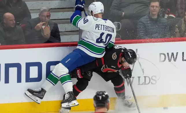 Vancouver Canucks centre Elias Pettersson (40) collides with Ottawa Senators defenseman Nick Jensen (3) along the boards during first period NHL action in Ottawa, Tuesday, Jan. 13, 2026. (Adrian Wyld/The Canadian Press via AP)