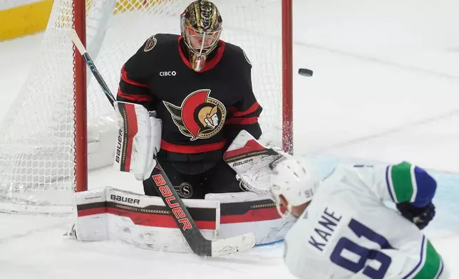 Vancouver Canucks left wing Evander Kane (91) shoots the puck wide of the net past Ottawa Senators goaltender Leevi Merilainen (1) during second period NHL action in Ottawa, Tuesday, Jan. 13, 2026. (Adrian Wyld/The Canadian Press via AP)