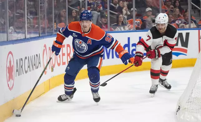 New Jersey Devils' Dougie Hamilton (7) chases Edmonton Oilers' Ryan Nugent-Hopkins (93) during the second period of an NHL hockey game in Edmonton on Tuesday, Jan. 20, 2026. (Jason Franson/The Canadian Press via AP)