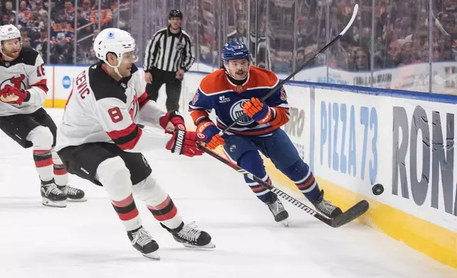 New Jersey Devils' Johnathan Kovacevic (8) and Edmonton Oilers' Isaac Howard (53) battle for the puck during the second period of an NHL hockey game in Edmonton on Tuesday, Jan. 20, 2026. (Jason Franson/The Canadian Press via AP)