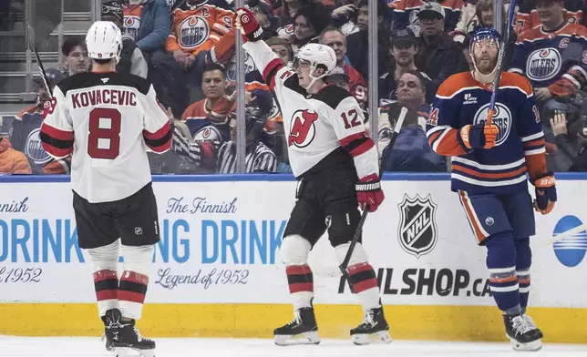 New Jersey Devils' Johnathan Kovacevic (8) and Cody Glass (12) celebrate a goal as Edmonton Oilers' Mattias Ekholm (14) looks on during the second period of an NHL hockey game in Edmonton, Alberta, on Tuesday, Jan. 20, 2026. (Jason Franson/The Canadian Press via AP)