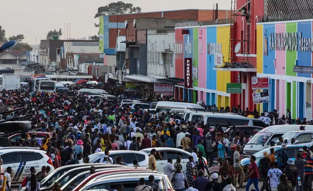 Commuters walk through parked vehicles during rush hour in downtown Harare, Zimbabwe, Tuesday, Dec. 16, 2025. (AP Photo/Aaron Ufumeli)