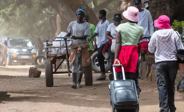 People walk on the sidewalk on the outskirts of Harare, Zimbabwe, Tuesday, Dec. 16, 2025. (AP Photo/Aaron Ufumeli)