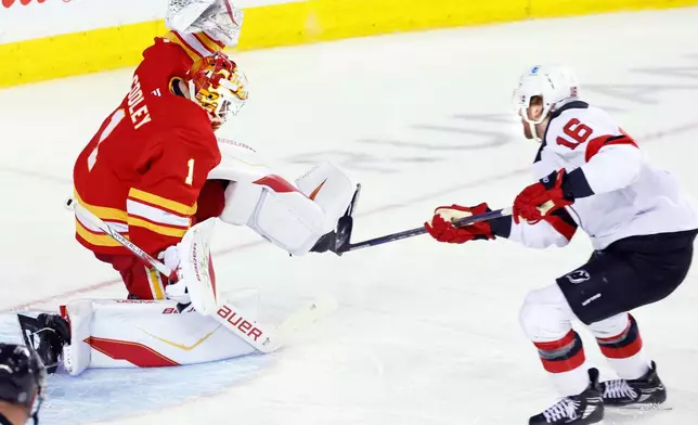 New Jersey Devils' Connor Brown, right, has a breakaway shot stopped by Calgary Flames goalie Devin Cooley (1) during second-period NHL hockey game action in Calgary, Alberta, Monday, Jan. 19, 2026. (Larry MacDougal/The Canadian Press via AP)
