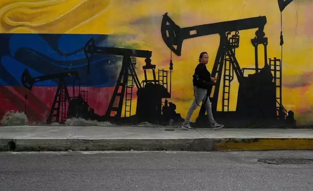 FILE - A local walks past a mural featuring oil pumps and wells in Caracas, Venezuela, Jan. 6, 2026. (AP Photo/Matias Delacroix, File)