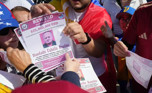 Reward posters are passed out at a gathering celebrating the deposing of Venezuelan President Nicolás Maduro, Sunday, Jan. 4, 2026, in Katy, Texas. (Elizabeth Conley/Houston Chronicle via AP)