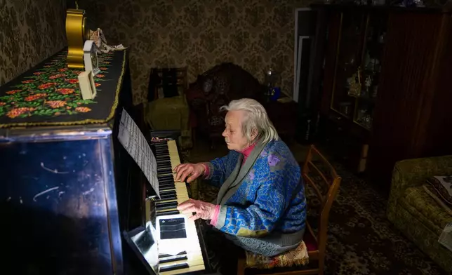 Raisa Derhachova plays the piano during a power outage caused by Russia's regular air strikes on the country's energy facilities in Kyiv, Ukraine, Tuesday, Jan. 13, 2026. (AP Photo/Dan Bashakov)