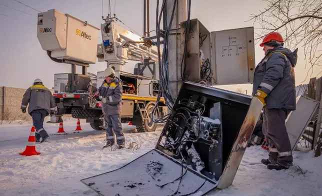 Electricians carry out emergency repairs on a power pole after a transformer burned out due to a voltage surge caused by regular Russian air attacks on the country's energy infrastructure in Kyiv region, Ukraine, Wednesday, Jan. 14, 2026. (AP Photo/Dan Bashakov)