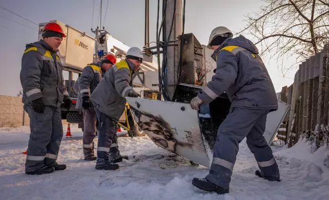 Electricians carry out emergency repairs on a power pole after a transformer burned out due to a voltage surge caused by regular Russian air attacks on the country's energy infrastructure in Kyiv region, Ukraine, Wednesday, Jan. 14, 2026. (AP Photo/Dan Bashakov)