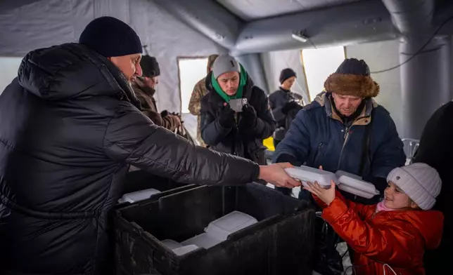 Residents get free food at an emergency center set up to support people during power outages caused by Russia's regular air attacks on the country's energy objects in Boryspil, Ukraine, Wednesday, Jan. 14, 2026. (AP Photo/Dan Bashakov)