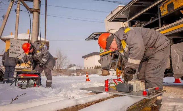 Electricians carry out emergency repairs on a power pole after a transformer burned out due to a voltage surge caused by regular Russian air attacks on the country's energy infrastructure in Kyiv region, Ukraine, Wednesday, Jan. 14, 2026. (AP Photo/Dan Bashakov)