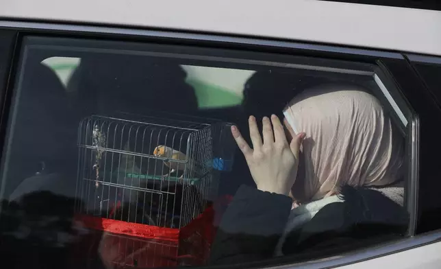 A woman sits in a car with her bird as she is fleeing from Sheikh Maqsoud and Achrafieh neighborhoods, after clashes broke out on Tuesday between Syrian government forces and Kurdish fighters in a contested area of the northern city of Aleppo, Syria, Wednesday, Jan. 7, 2026. (AP Photo/Omar Albam)