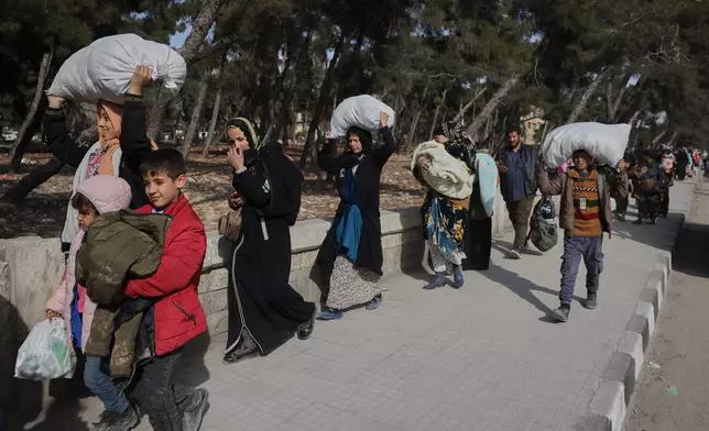 Residents carry their belongings as they are fleeing from Sheikh Maqsoud and Achrafieh neighborhoods after clashes broke out on Tuesday between Syrian government forces and Kurdish fighters in a contested area of the northern city of Aleppo, Syria, Wednesday, Jan. 7, 2026. (AP Photo/Omar Albam)
